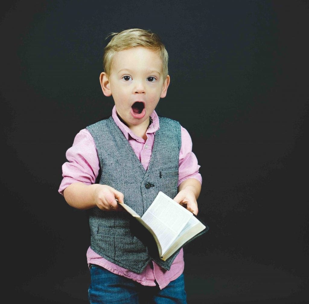 Boy Holding Book looking Surprised